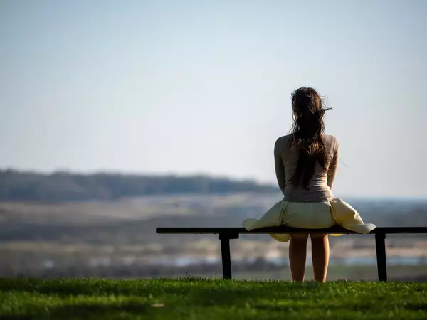 woman-sitting-alone-on-bench-outside.webp